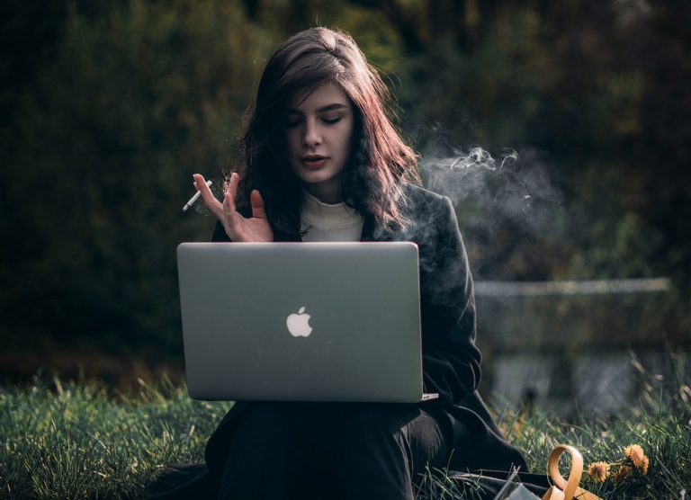 Woman looking at laptop while smoking